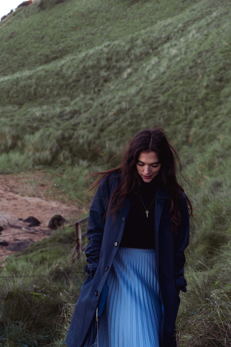 Walking through green hills in a navy coat